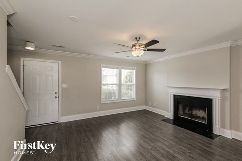 A spacious living room with a fireplace and a ceiling fan.