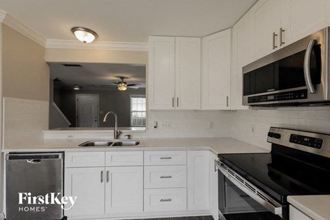 A kitchen with white cabinets and black appliances.