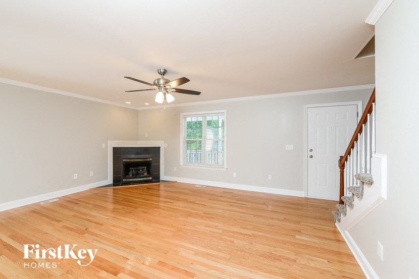 an empty living room with a ceiling fan and a fireplace