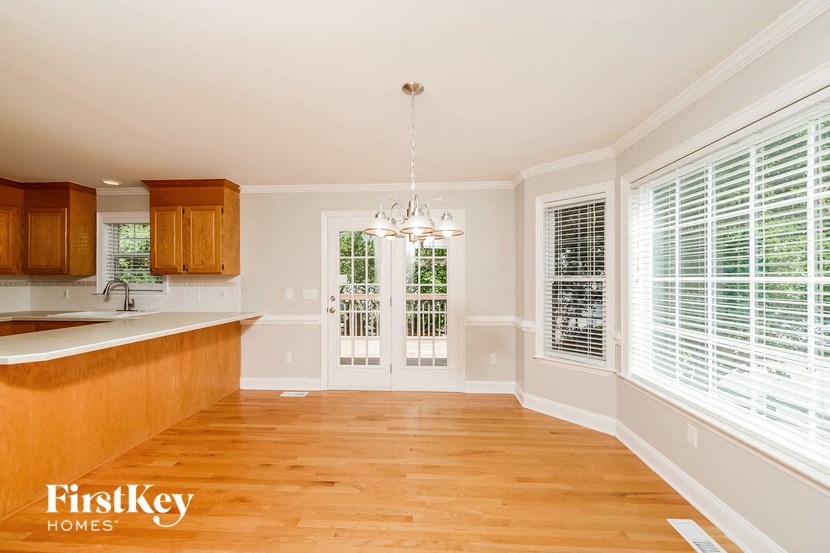 an empty dining room and kitchen with wood floors and windows
