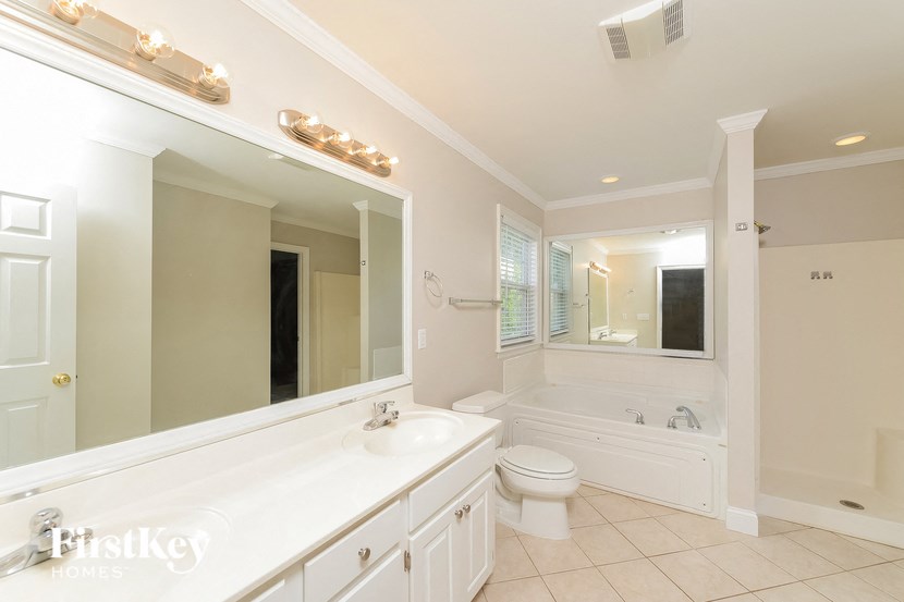 a white bathroom with a large mirror and a toilet and a sink