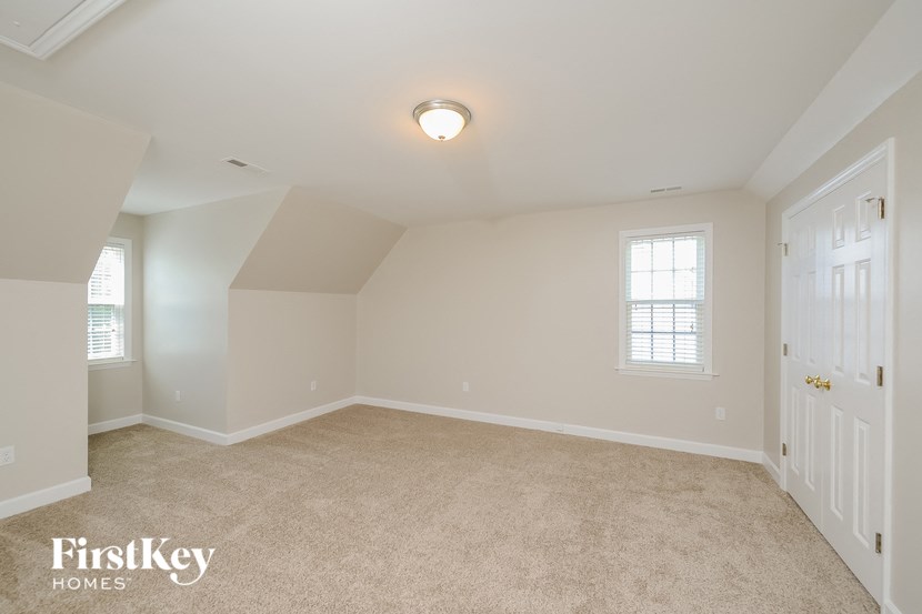 a spacious bedroom with white walls and carpeting and a white door