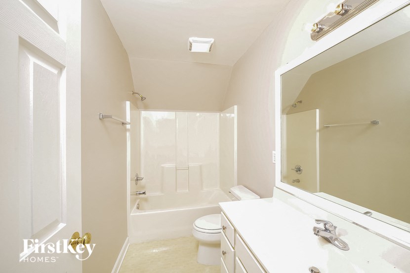 a white bathroom with a white toilet and a large mirror