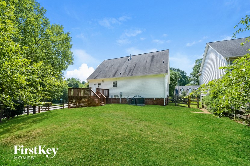 a backyard with a white house and a green lawn