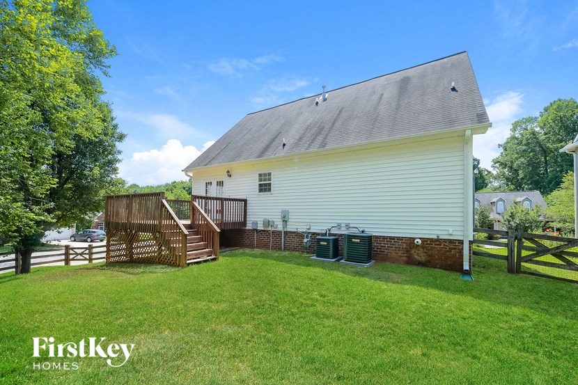 the back of a white house with a yard and a fence