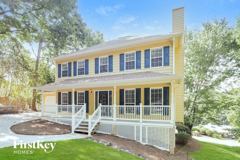 a yellow house with black shutters and a white fence