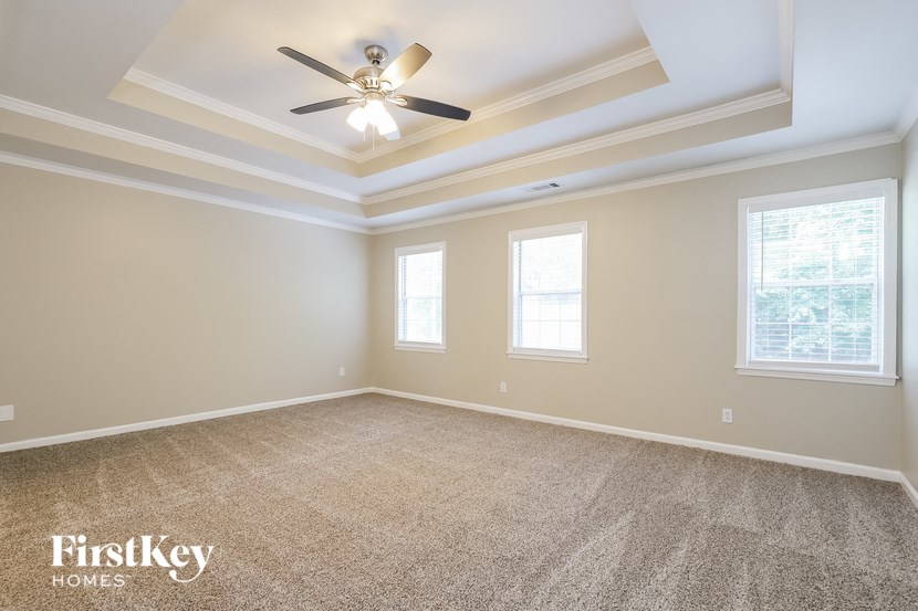 an empty living room with a ceiling fan and windows