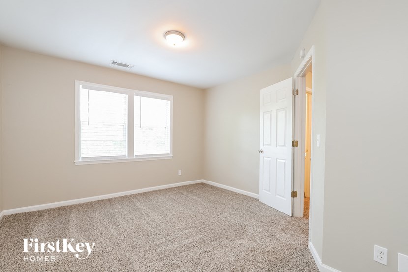 a bedroom with a white door and a window and a carpeted floor