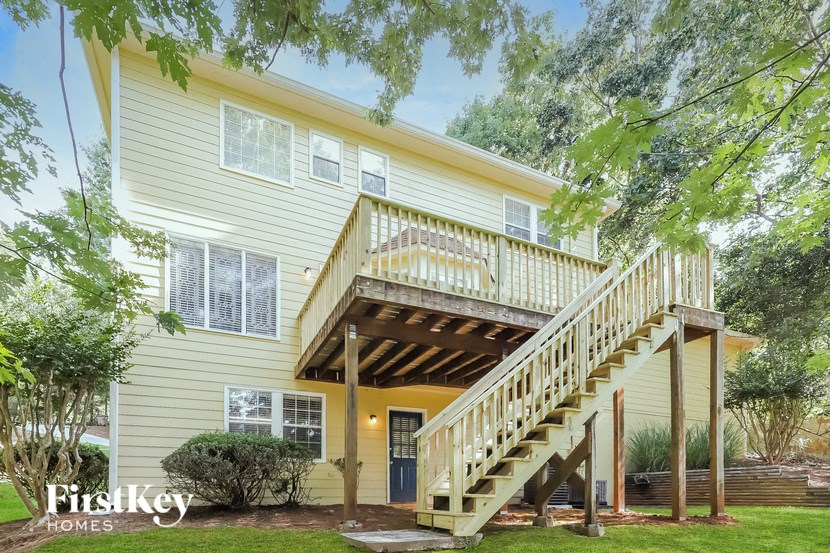 a yellow house with a deck and a staircase