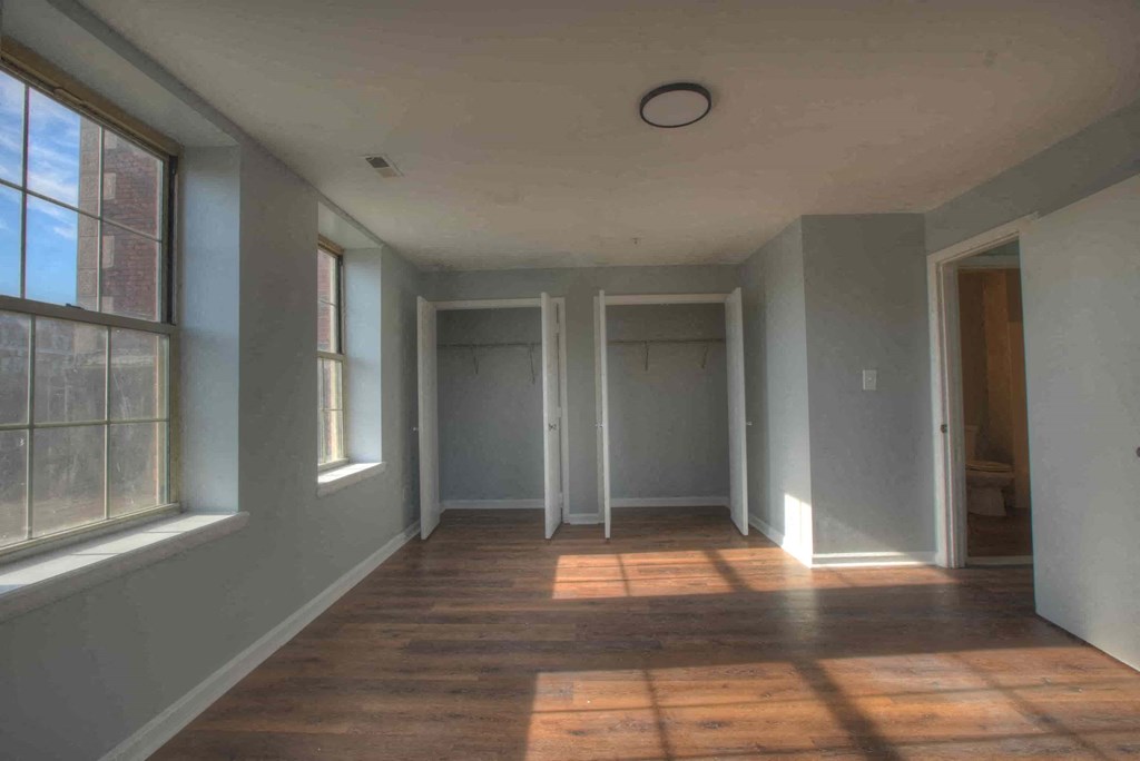 an empty room with a hard wood floor and three doors