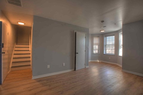 an empty living room with wood floors and a staircase