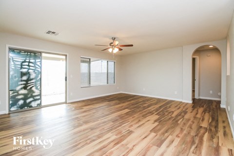 A spacious room with wooden flooring and a ceiling fan.