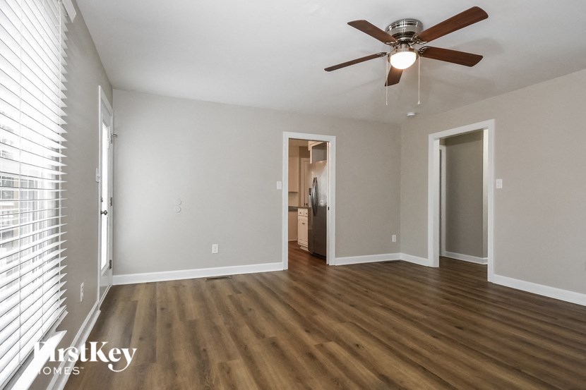 an empty living room with wood floors and a ceiling fan