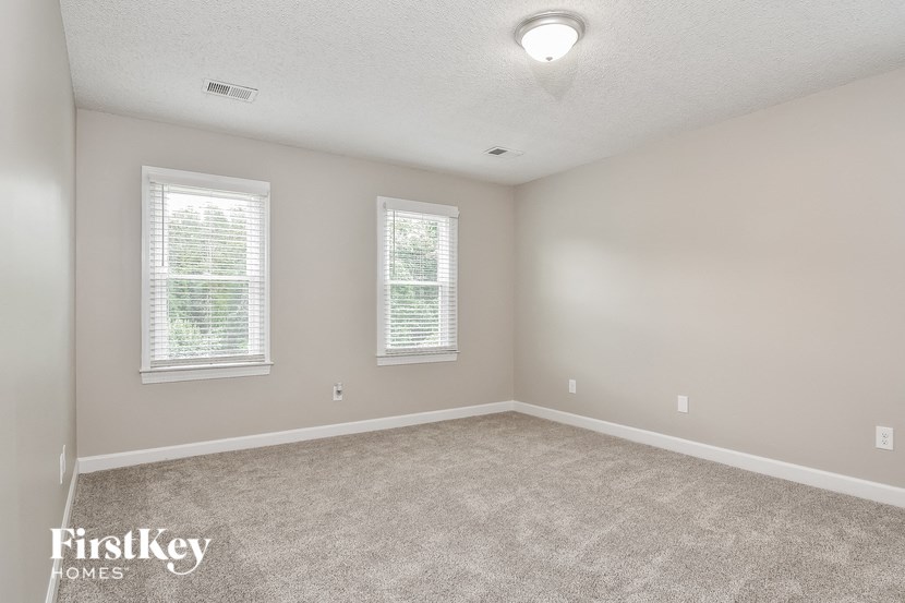 a bedroom with carpet and two windows