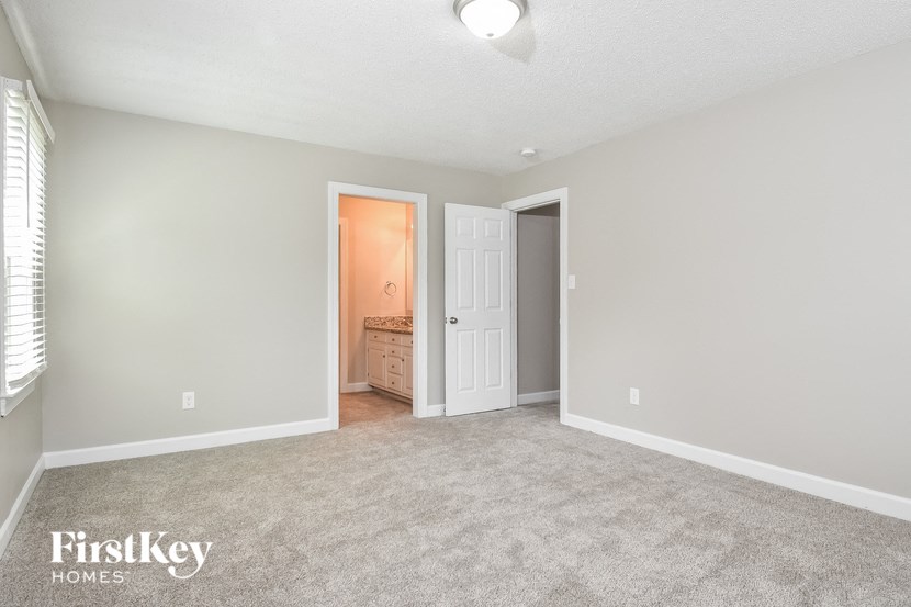 an empty living room with a door to a bathroom