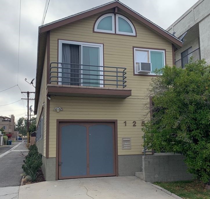 a yellow house with a balcony and a garage door