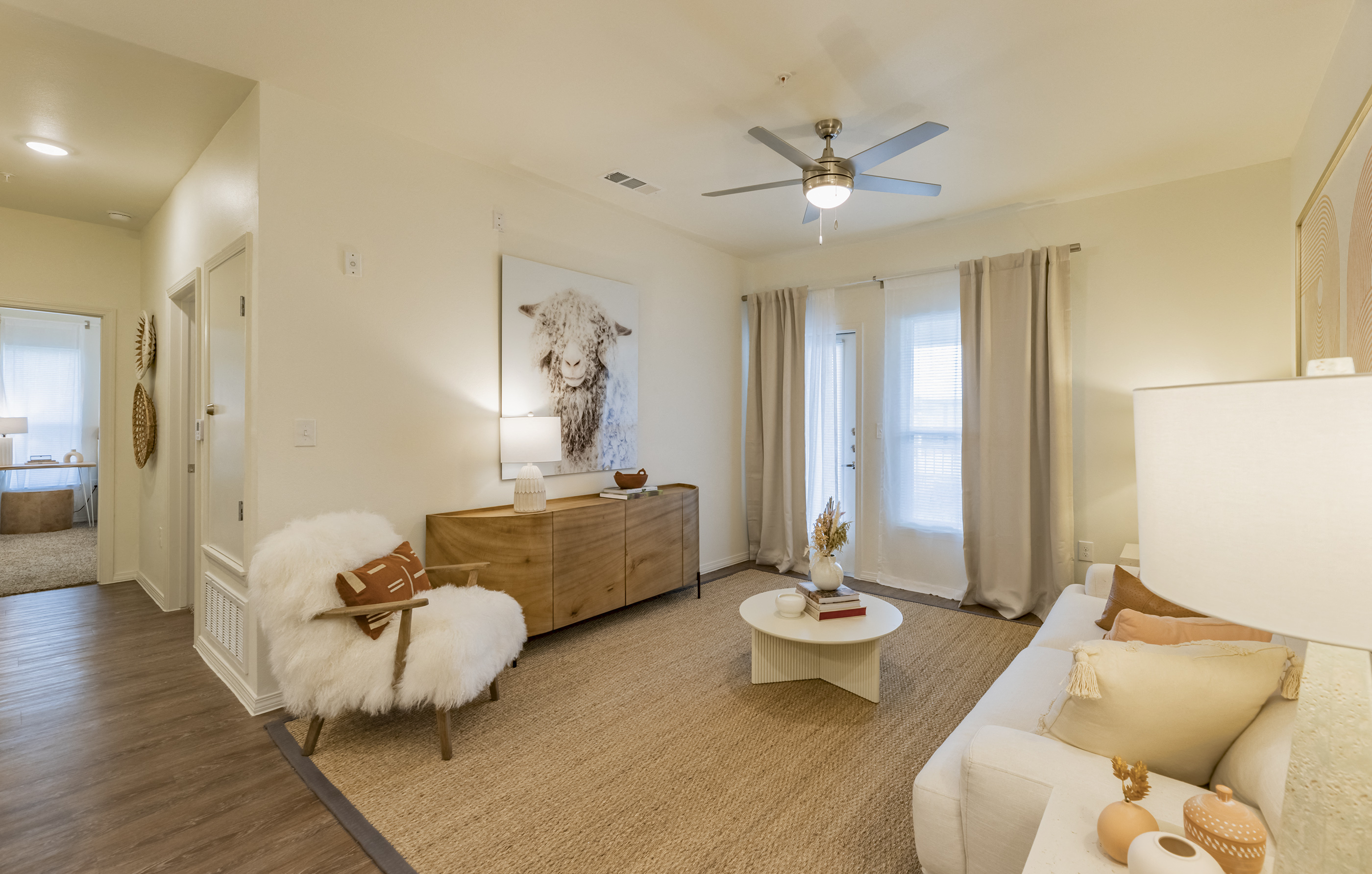a living room with white furniture and a ceiling fan