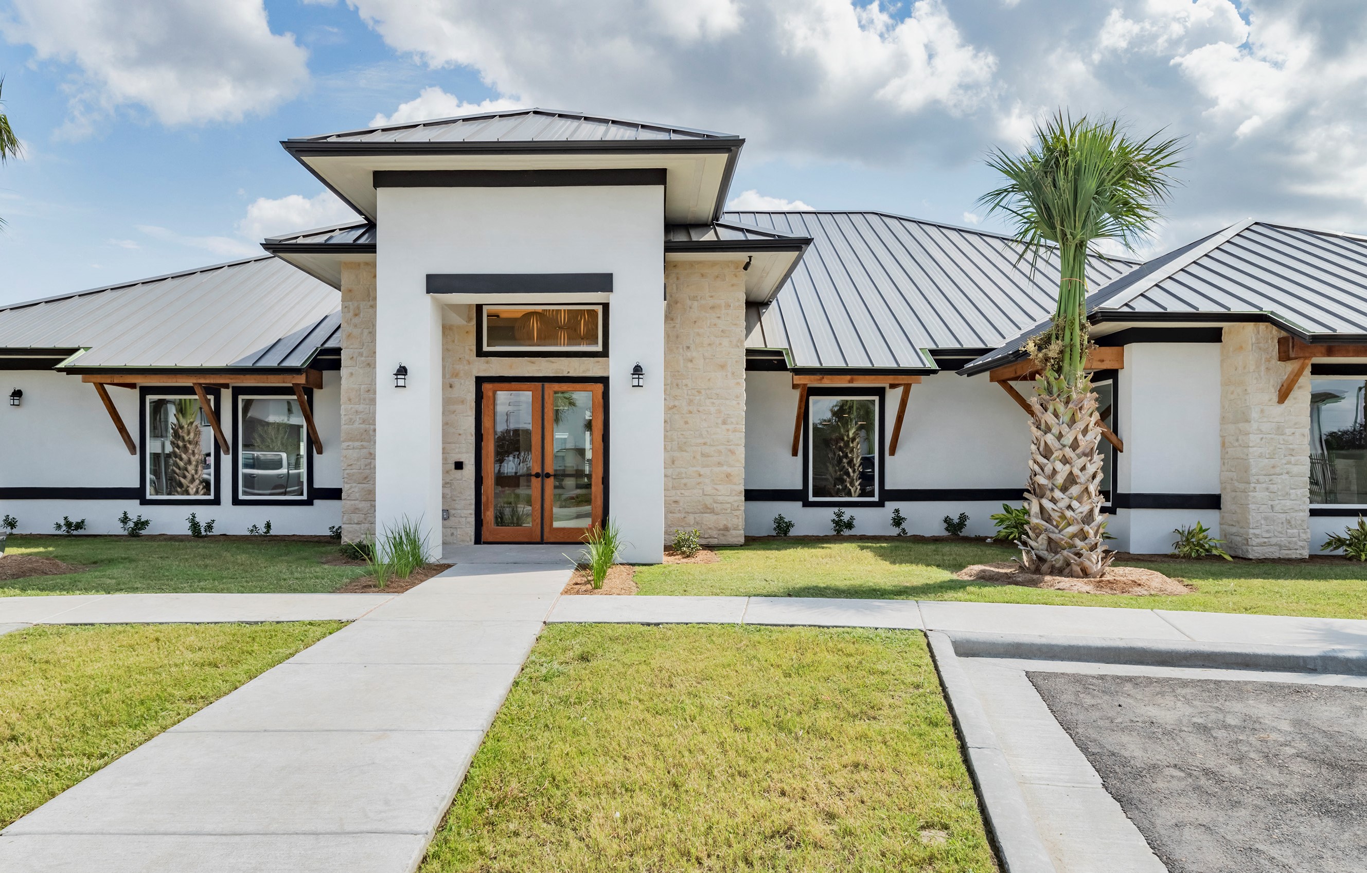 the front of a house with a sidewalk and a palm tree