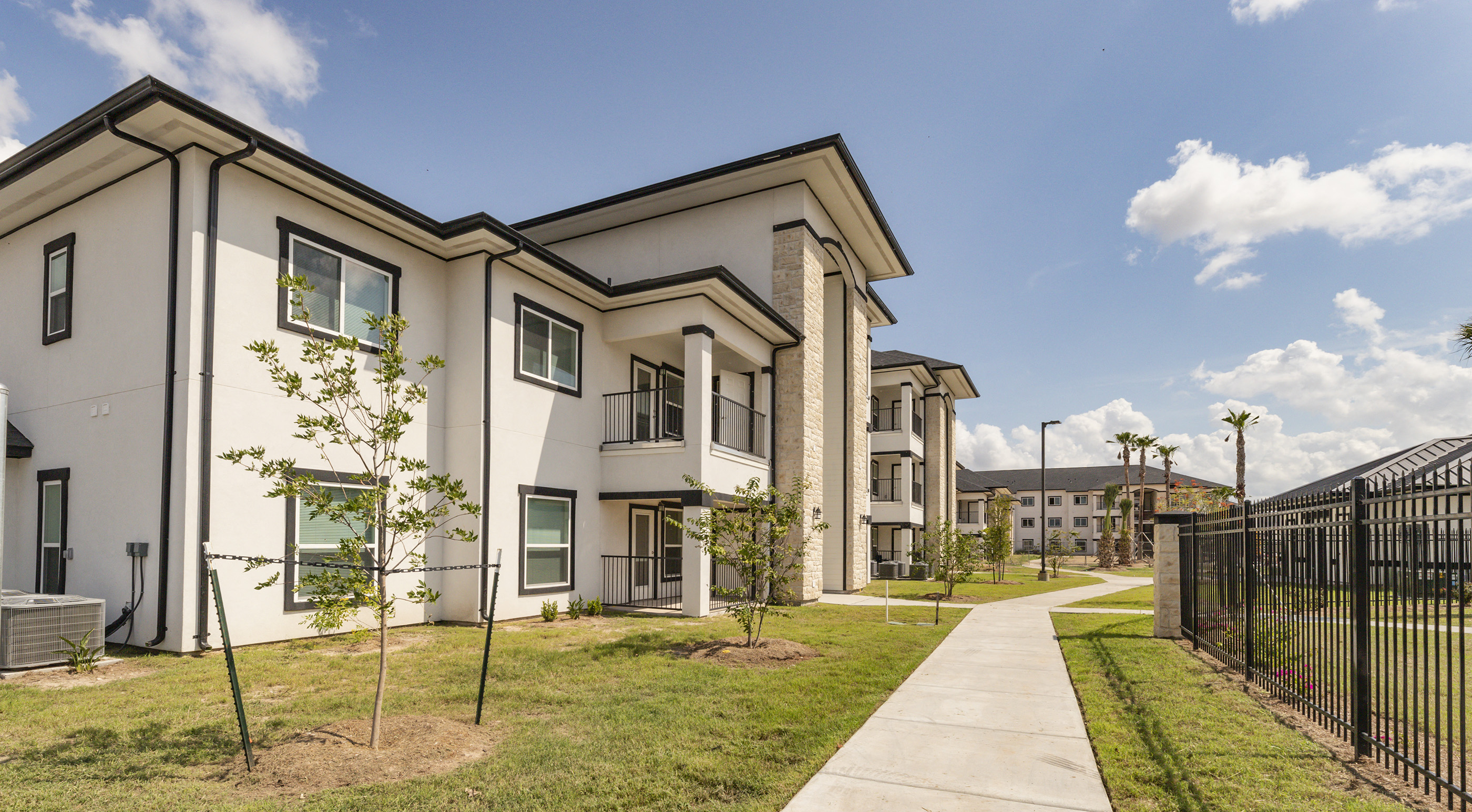 a row of townhomes with a sidewalk and grass