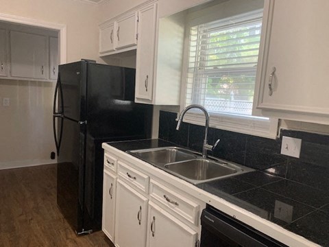 a kitchen with a sink and a black refrigerator