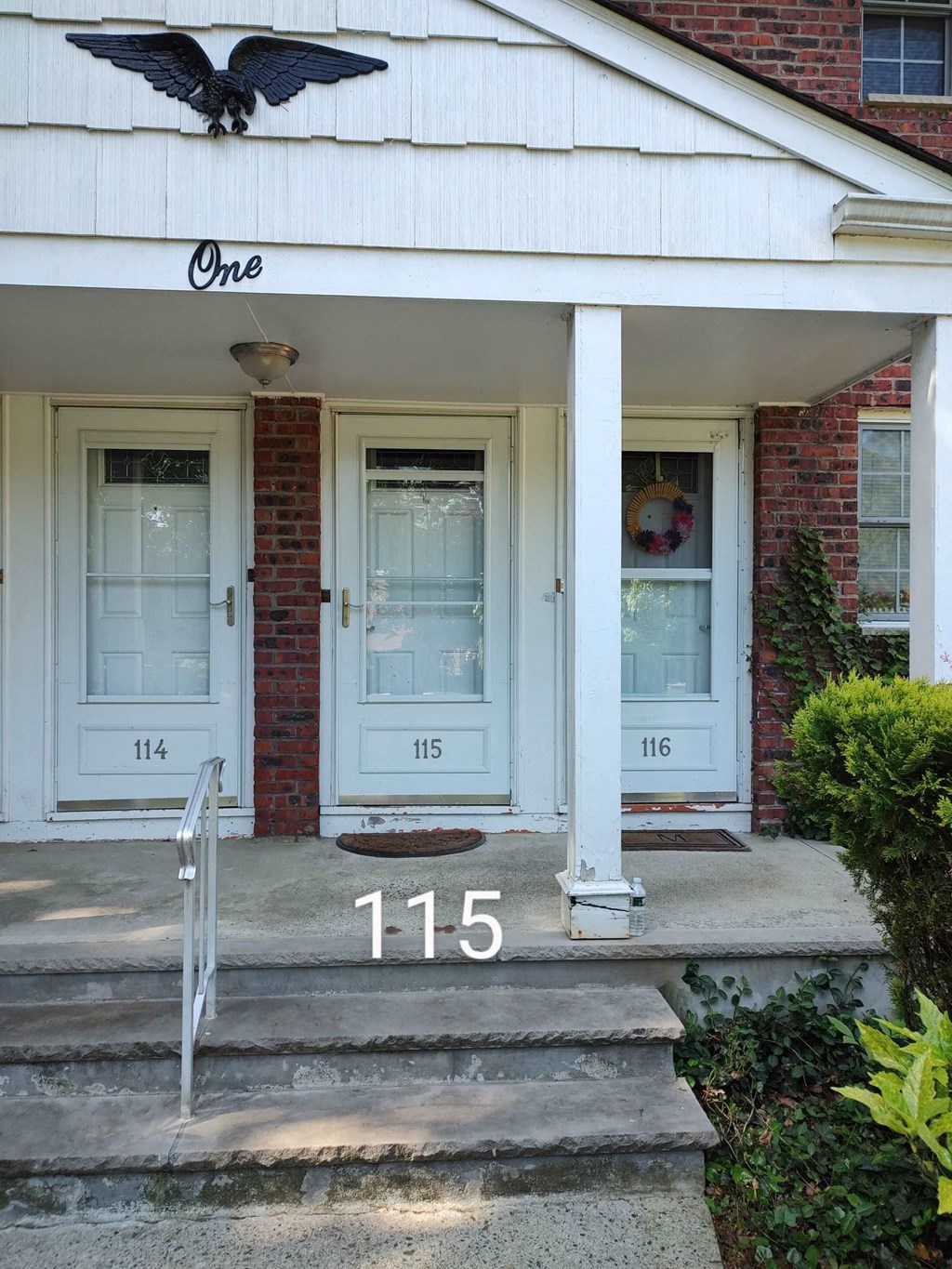 the front door of a house with the number 115 on the steps