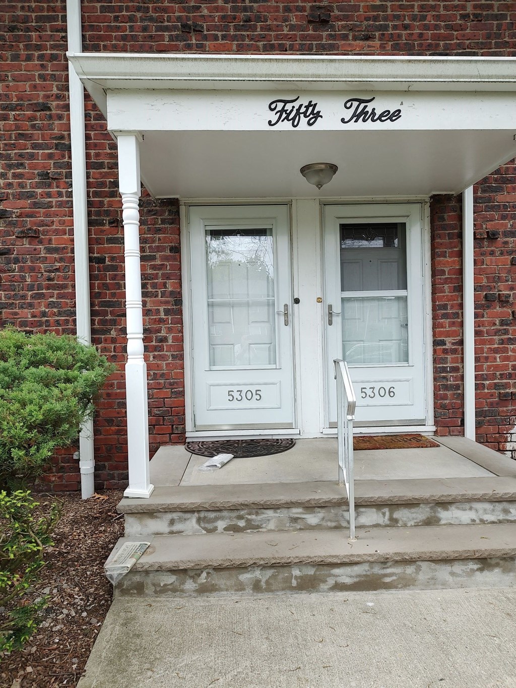 the front of a brick house with white doors and a porch