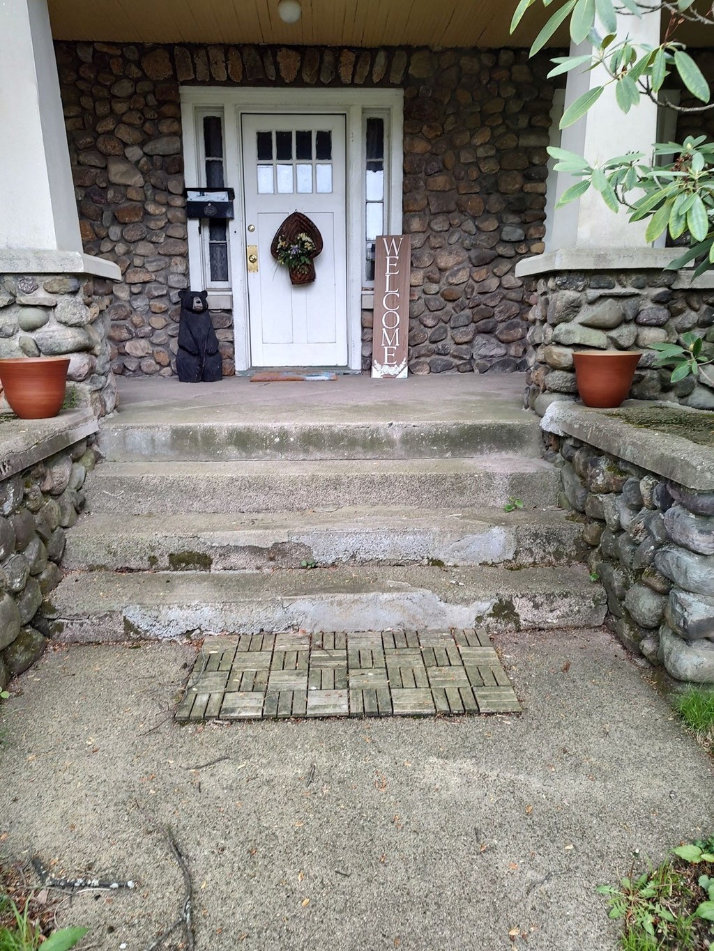 A stone house with a white door and a welcome mat.