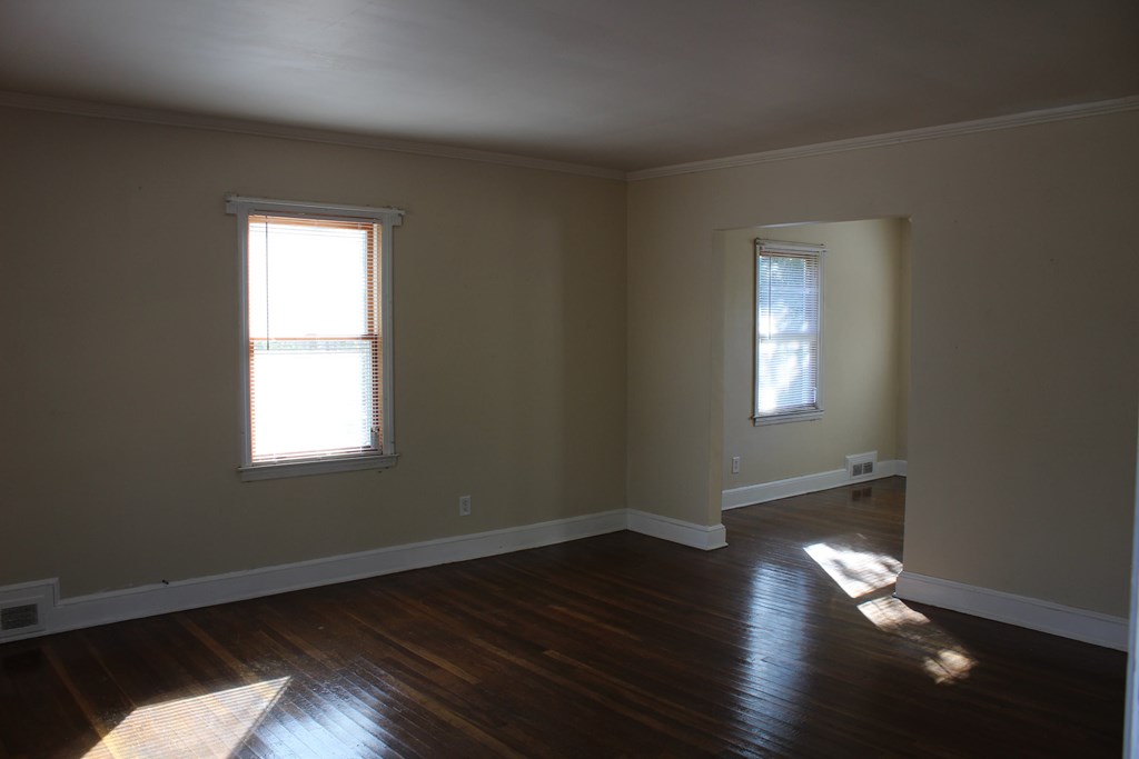 an empty living room with wood floors and two windows