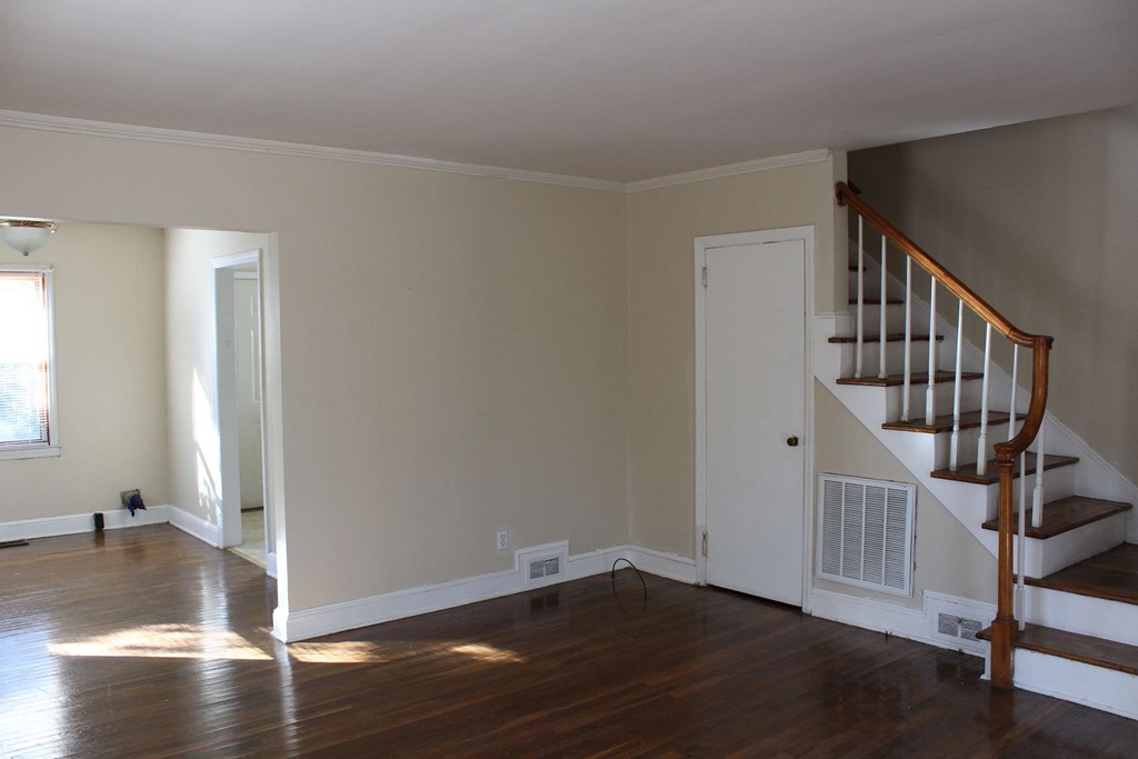 an empty living room with a staircase and wood floors