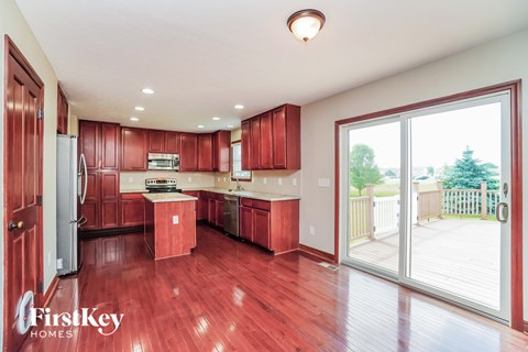 A kitchen with red cabinets and a wooden floor.