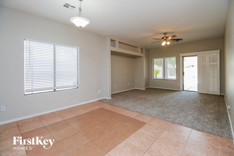 an empty living room with a ceiling fan and a door to a patio