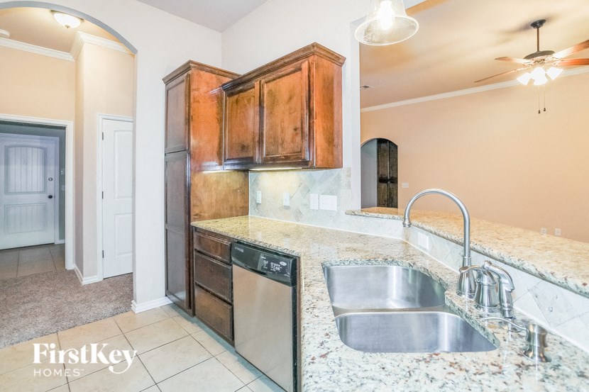 a kitchen with a sink and a dishwasher and wooden cabinets