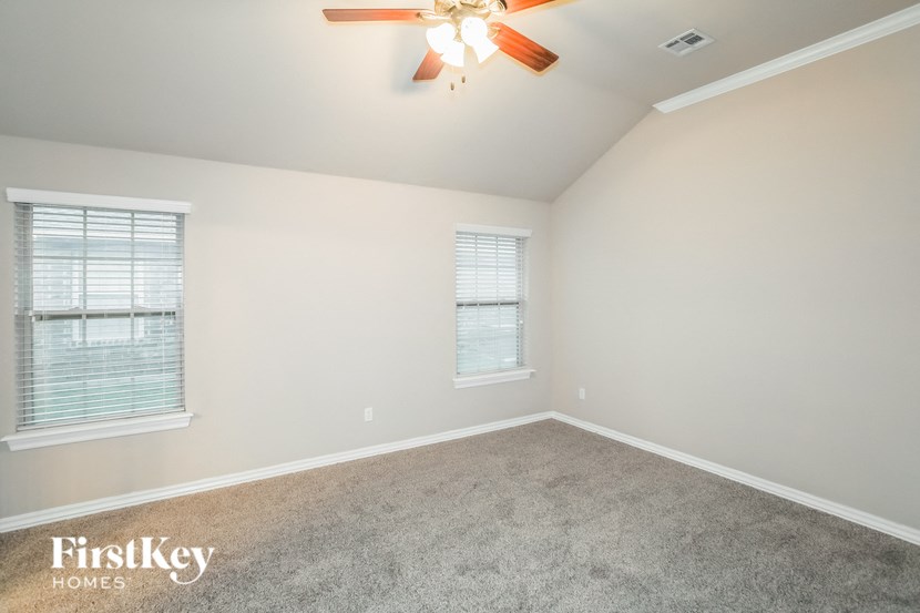 an empty room with two windows and a ceiling fan