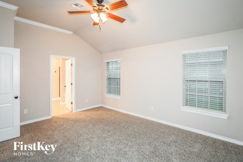 an empty room with a ceiling fan and a door to a hallway