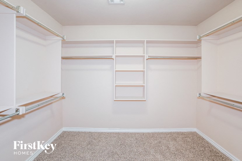a large walk in closet with empty shelves and carpet
