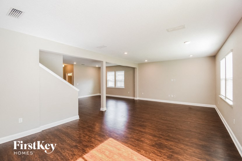 the living room and dining room with wood flooring and white walls