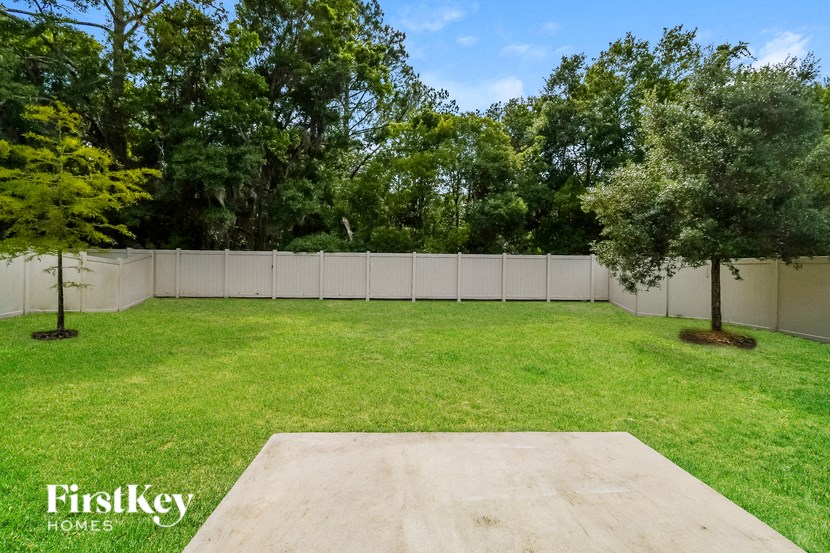 a backyard with green grass and a fence and trees