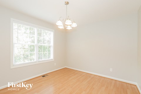 A room with wooden floors and a window with blinds.