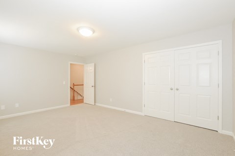 A white bedroom with a doorway leading to another room.