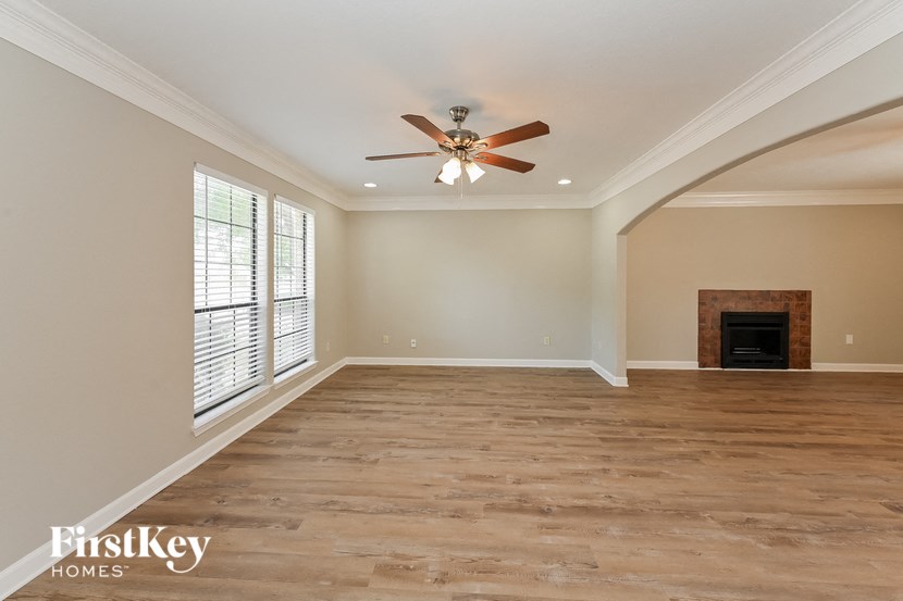 an empty living room with a ceiling fan and a fireplace