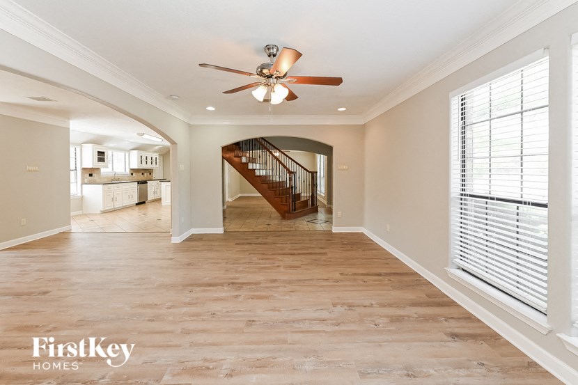an empty living room with a ceiling fan and a staircase