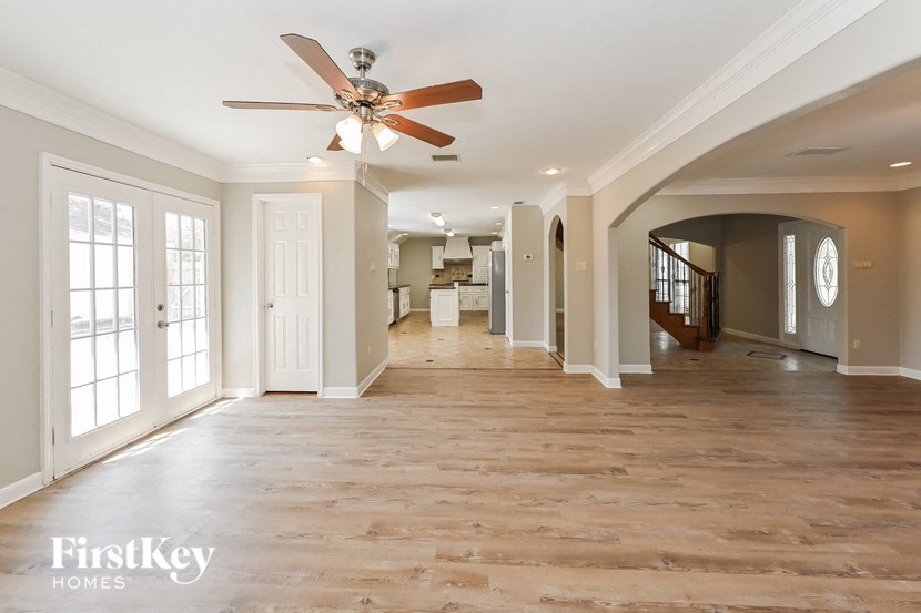 an empty living room with wood floors and a ceiling fan