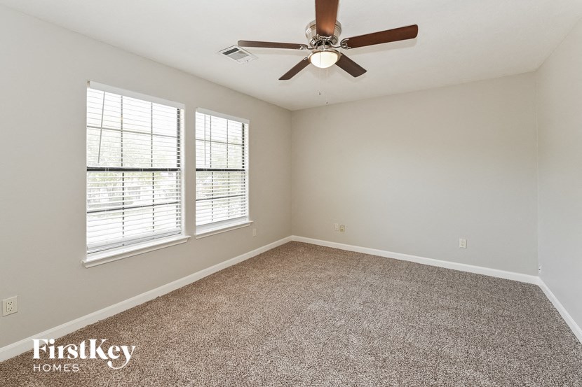 an empty room with a ceiling fan and two windows