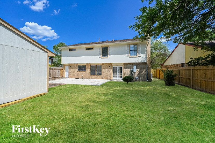 a backyard with a lawn and a white house