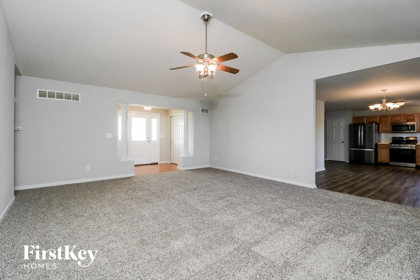 an empty living room with a ceiling fan