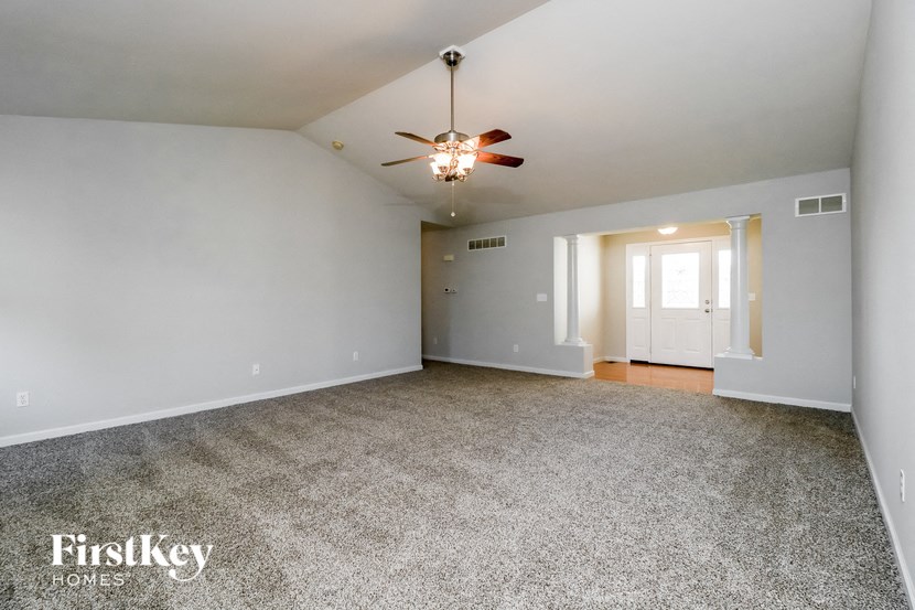 a empty living room with a ceiling fan and white walls