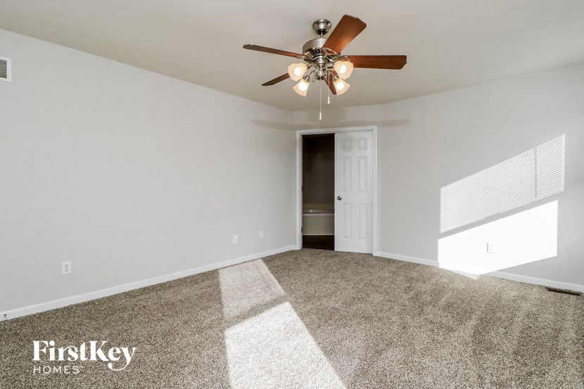 the spacious living room with ceiling fan and carpet