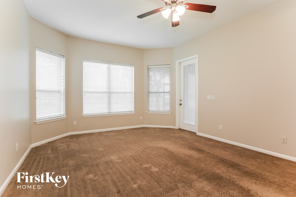 A room with a ceiling fan and three windows.