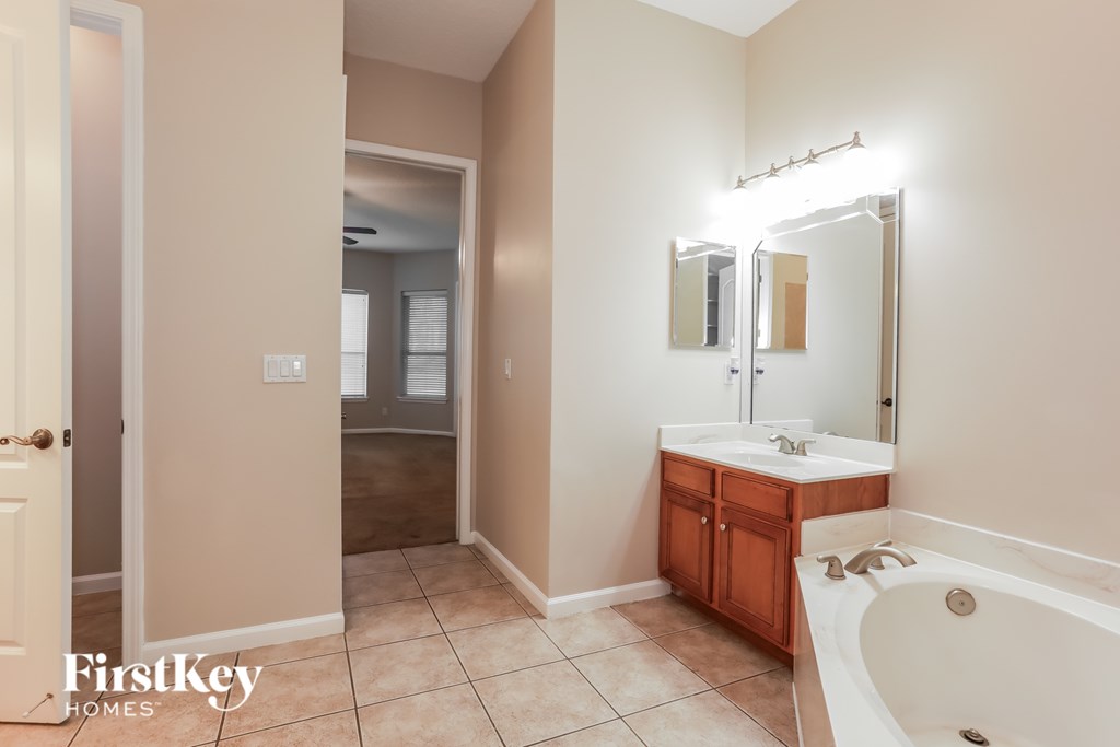 A bathroom with a tub, sink, and mirror.