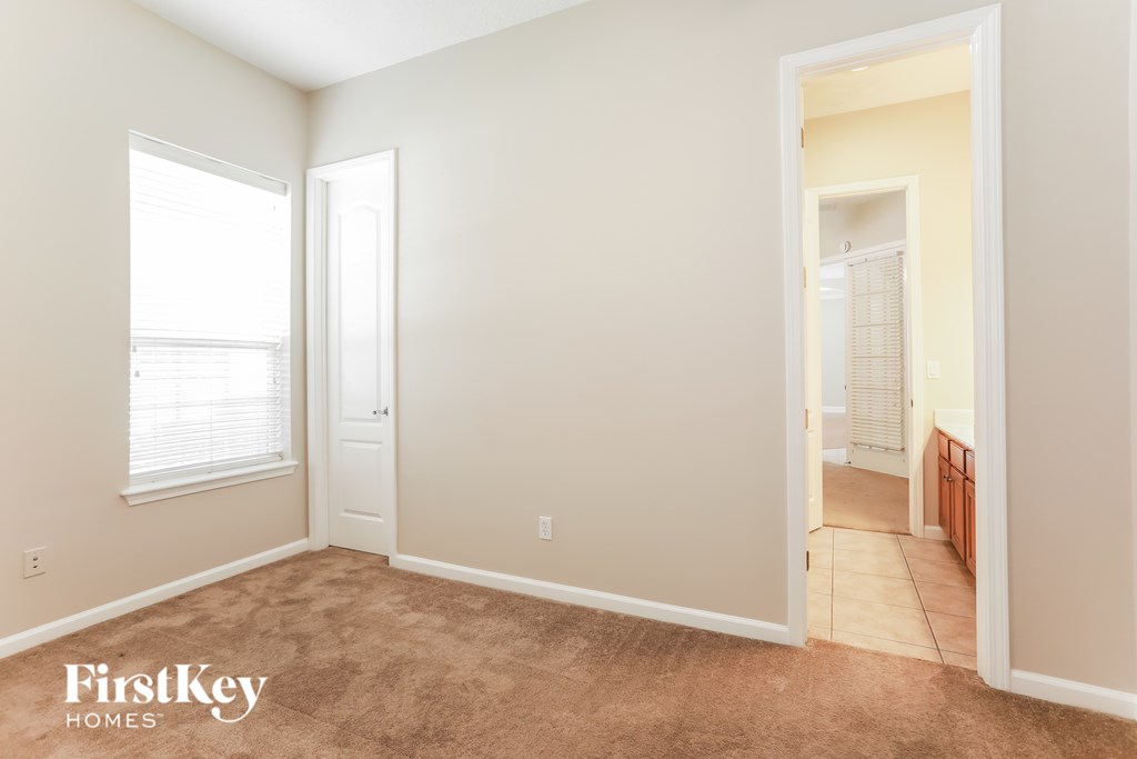 A room with a carpeted floor and a door leading to another room.